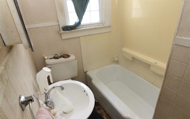 bathroom featuring a washtub, toilet, and tile walls