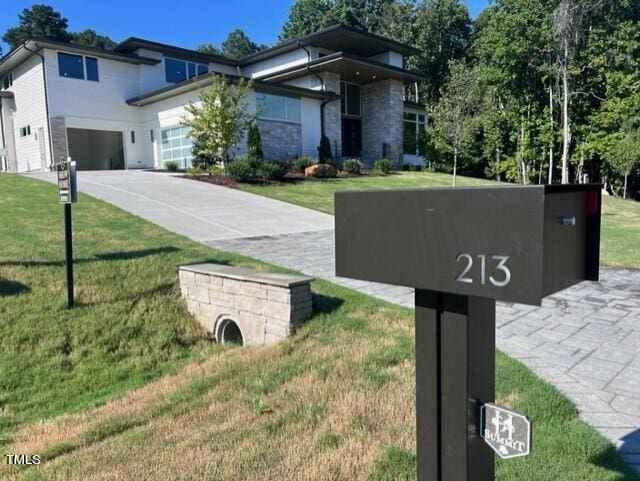 view of front of property featuring a garage, concrete driveway, and a front yard