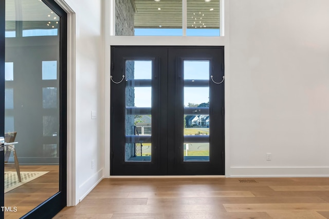 foyer featuring a high ceiling, wood finished floors, visible vents, baseboards, and french doors