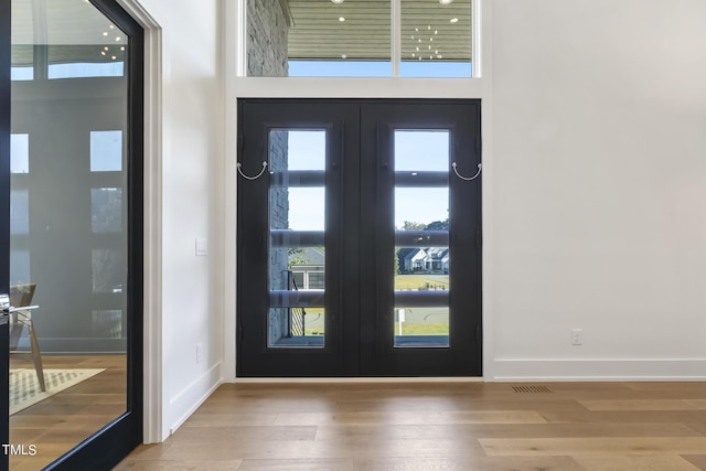 foyer entrance featuring french doors, baseboards, and wood finished floors