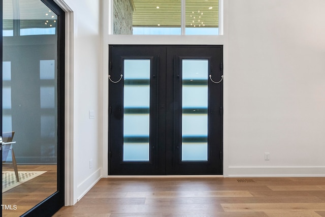 foyer entrance featuring a healthy amount of sunlight, wood finished floors, and french doors