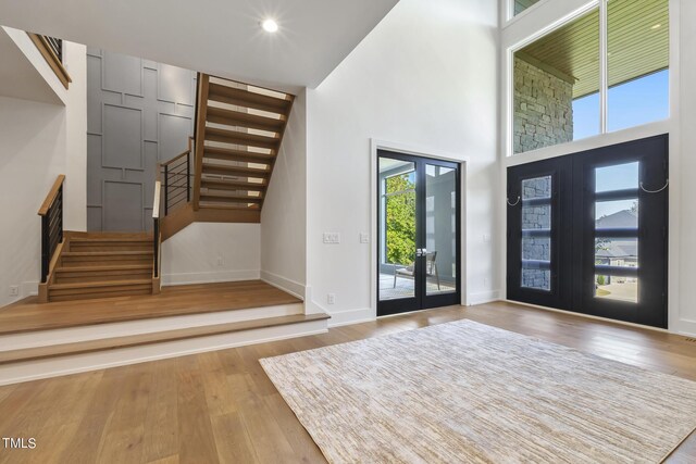 foyer entrance with stairs, french doors, and wood finished floors