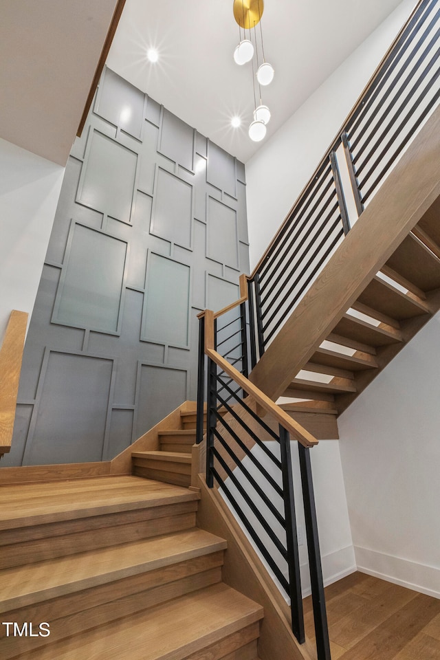 staircase featuring a decorative wall, recessed lighting, wood finished floors, and baseboards