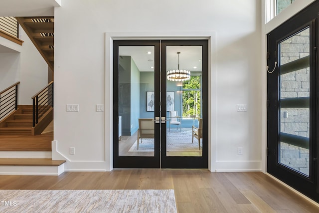 entryway featuring baseboards, stairway, french doors, wood finished floors, and a notable chandelier