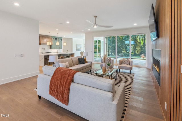 living area featuring recessed lighting, a large fireplace, baseboards, and wood finished floors