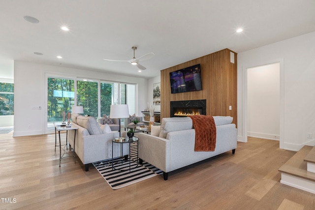 living room with baseboards, recessed lighting, a fireplace, and light wood-style floors