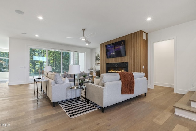 living area with recessed lighting, a fireplace, light wood-style flooring, and a ceiling fan