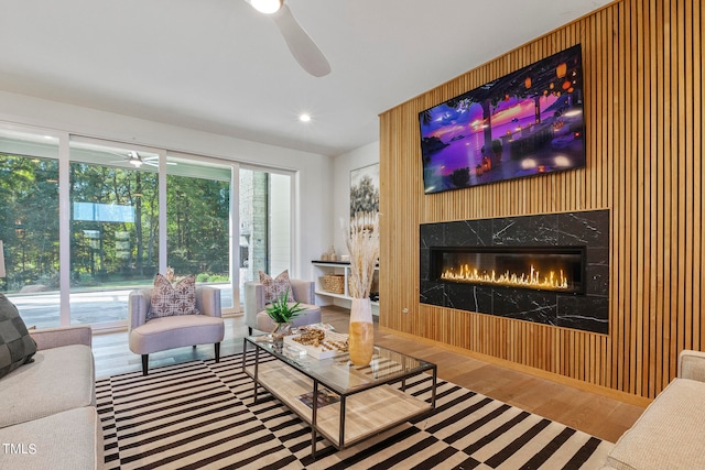 living room with ceiling fan, a premium fireplace, and wood finished floors