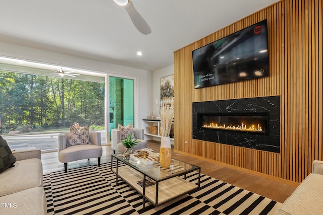 living room with ceiling fan, wood finished floors, and a high end fireplace