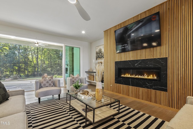 living room featuring wood finished floors, ceiling fan, and a premium fireplace