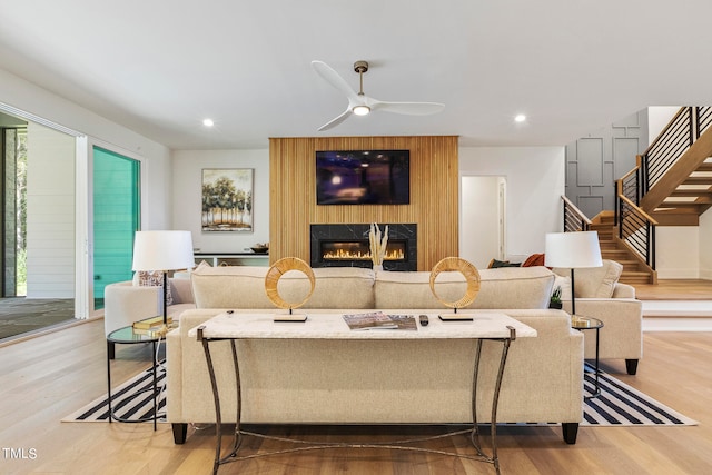 living room with recessed lighting, a large fireplace, ceiling fan, wood finished floors, and stairs