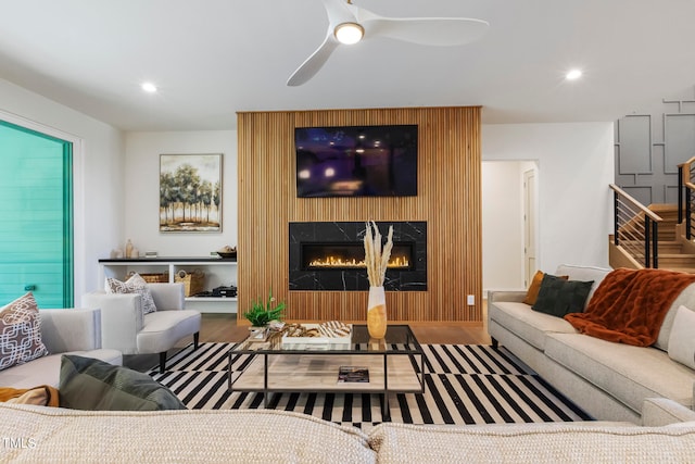 living area with recessed lighting, ceiling fan, stairs, and a high end fireplace