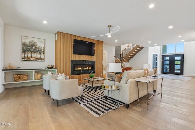 living area featuring french doors, a fireplace, recessed lighting, wood finished floors, and stairs