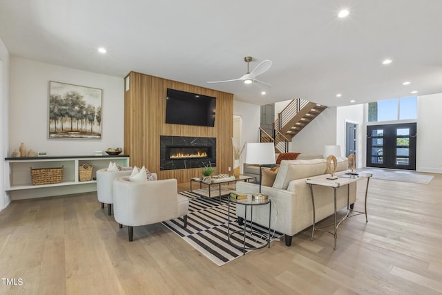 living room featuring wood finished floors, recessed lighting, a fireplace, ceiling fan, and stairs