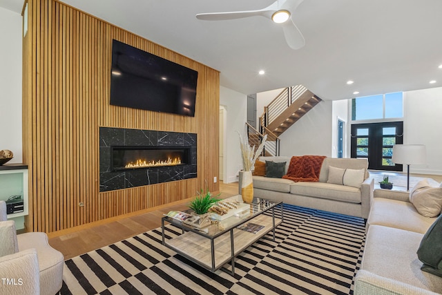 living area with recessed lighting, stairway, a ceiling fan, wood finished floors, and a tile fireplace