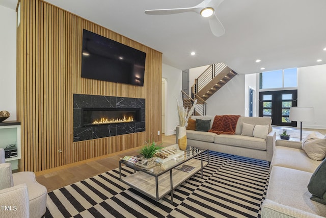 living area with a ceiling fan, wood finished floors, recessed lighting, a premium fireplace, and stairs