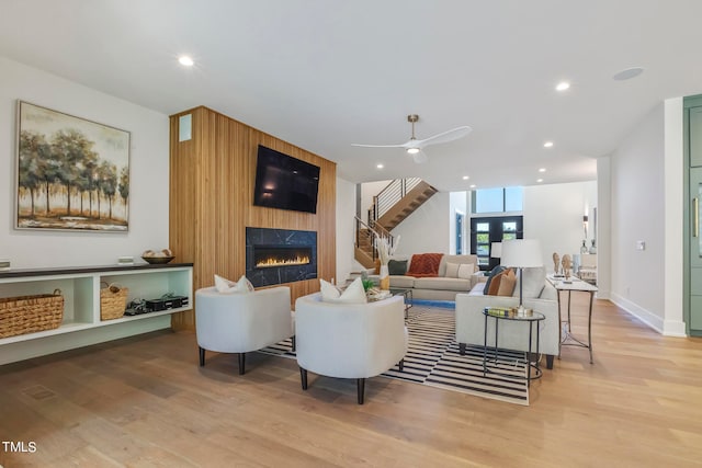 living area featuring a fireplace, recessed lighting, ceiling fan, light wood-type flooring, and stairs