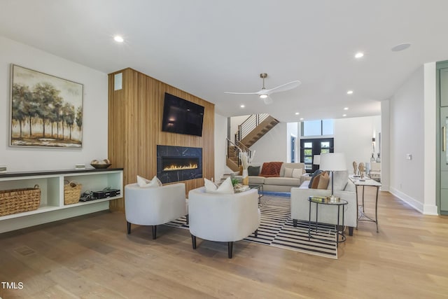 living room with recessed lighting, light wood-style floors, a fireplace, ceiling fan, and stairs