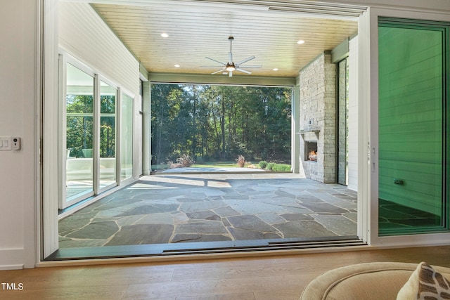 doorway with wooden ceiling, ceiling fan, stone finish floor, an outdoor stone fireplace, and recessed lighting