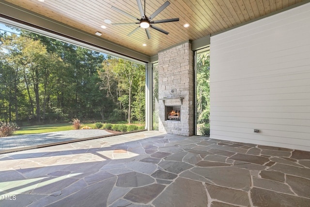 view of patio featuring an outdoor stone fireplace and a ceiling fan