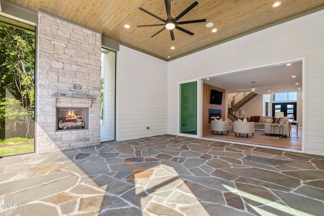 view of patio / terrace featuring a ceiling fan and an outdoor stone fireplace