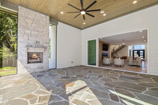 view of patio / terrace featuring an outdoor stone fireplace and a ceiling fan