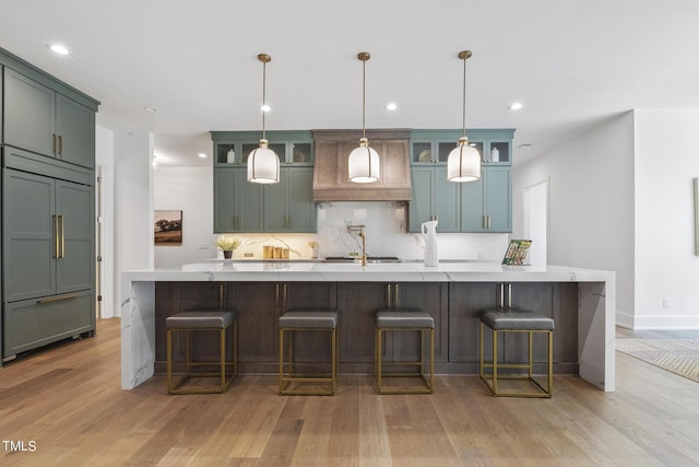 kitchen with a spacious island, backsplash, light wood-type flooring, and built in fridge