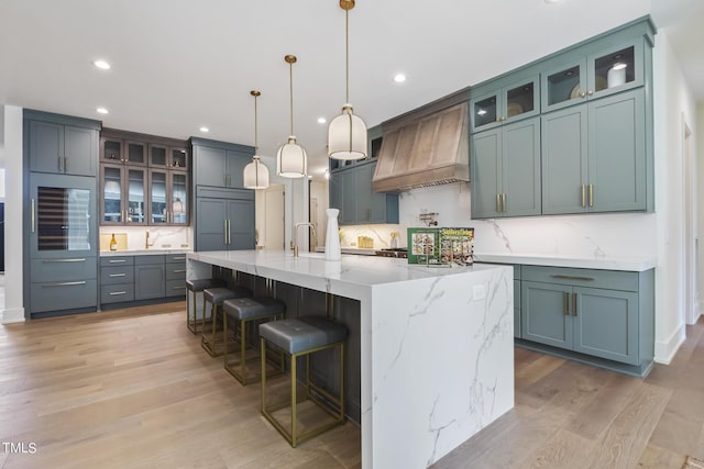 kitchen featuring premium range hood, light wood-style flooring, oven, built in refrigerator, and tasteful backsplash