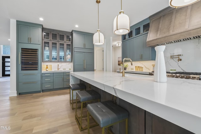 kitchen featuring paneled fridge, light stone counters, beverage cooler, and a sink