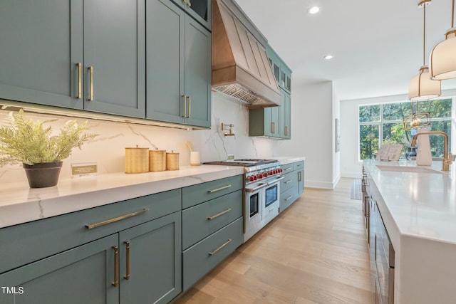 kitchen featuring decorative backsplash, range with two ovens, custom range hood, light wood-style floors, and a sink