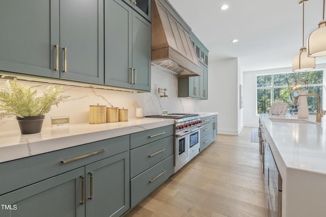 kitchen with premium range hood, range with two ovens, light wood-style flooring, a sink, and backsplash