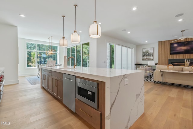 kitchen with recessed lighting, a sink, open floor plan, appliances with stainless steel finishes, and light wood finished floors