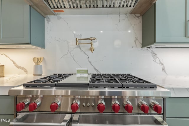 kitchen with decorative backsplash, light stone countertops, and range with two ovens