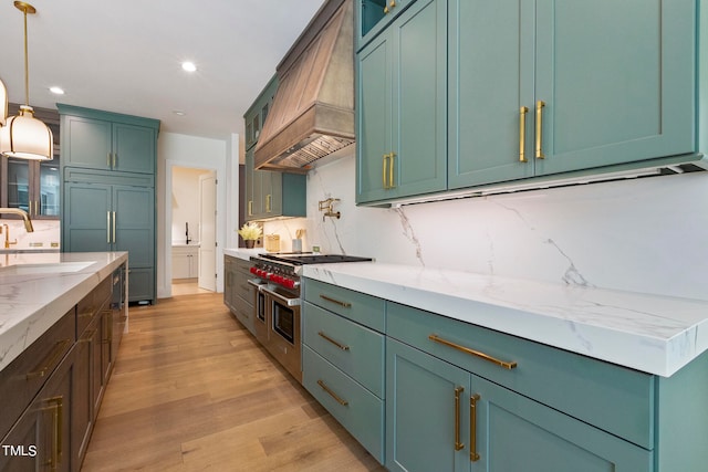 kitchen with custom exhaust hood, light wood-style flooring, decorative backsplash, a sink, and high quality appliances