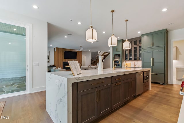 kitchen with light wood finished floors, built in fridge, a sink, stainless steel dishwasher, and recessed lighting