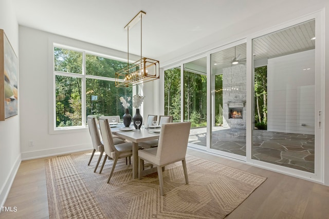 dining room with a notable chandelier, a fireplace, wood finished floors, and baseboards