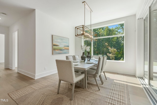 dining area with wood finished floors, a healthy amount of sunlight, baseboards, and an inviting chandelier