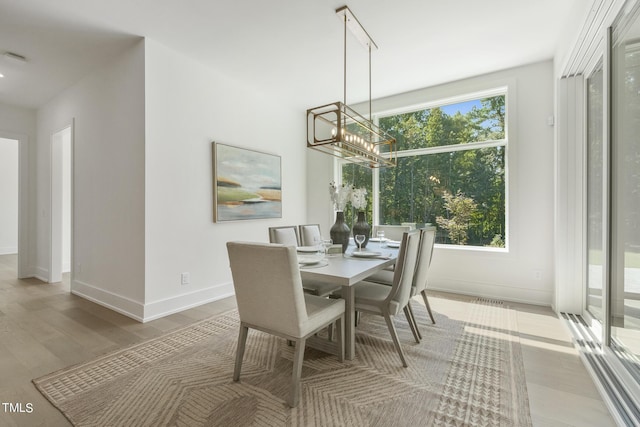 dining area featuring wood finished floors, a notable chandelier, a healthy amount of sunlight, and baseboards