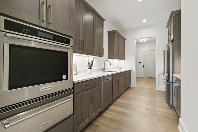 kitchen featuring stainless steel appliances, light wood-type flooring, light countertops, and a sink