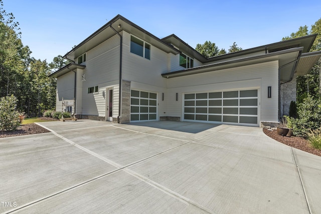 view of property exterior with concrete driveway, an attached garage, and stone siding