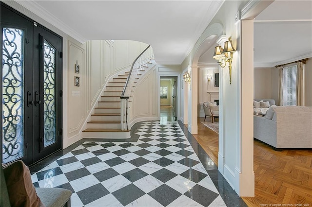 foyer entrance featuring dark parquet floors, crown molding, french doors, and a wealth of natural light