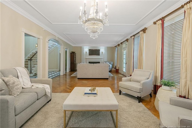 living room featuring crown molding, an inviting chandelier, light parquet floors, and ornate columns