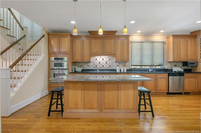 kitchen featuring hanging light fixtures, light hardwood / wood-style flooring, tasteful backsplash, and stainless steel appliances