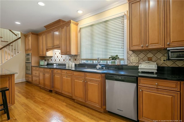 kitchen featuring sink, dark stone countertops, light hardwood / wood-style flooring, stainless steel appliances, and tasteful backsplash