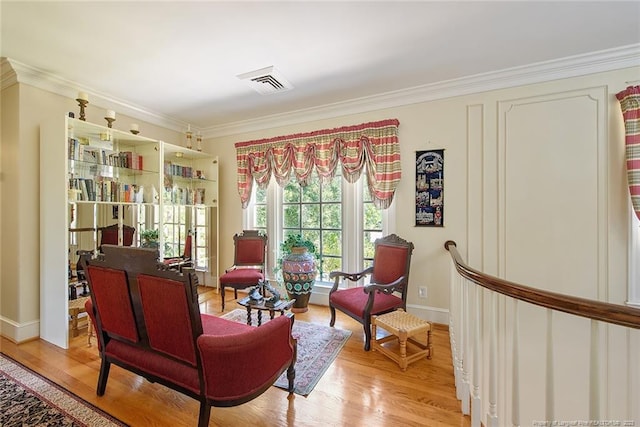 sitting room with crown molding and light hardwood / wood-style floors