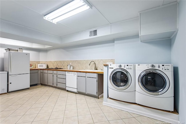 clothes washing area featuring light tile floors, washing machine and clothes dryer, and sink