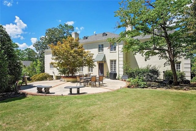 rear view of property featuring a lawn and a patio