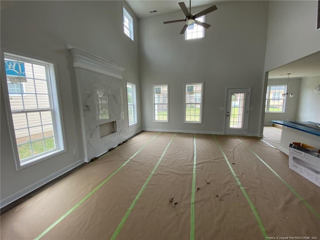 unfurnished living room featuring ceiling fan with notable chandelier and a towering ceiling