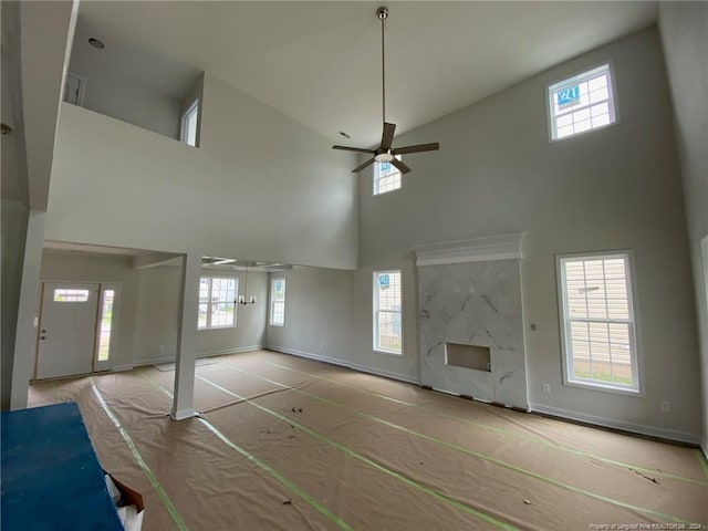 unfurnished living room with a high ceiling, plenty of natural light, and ceiling fan