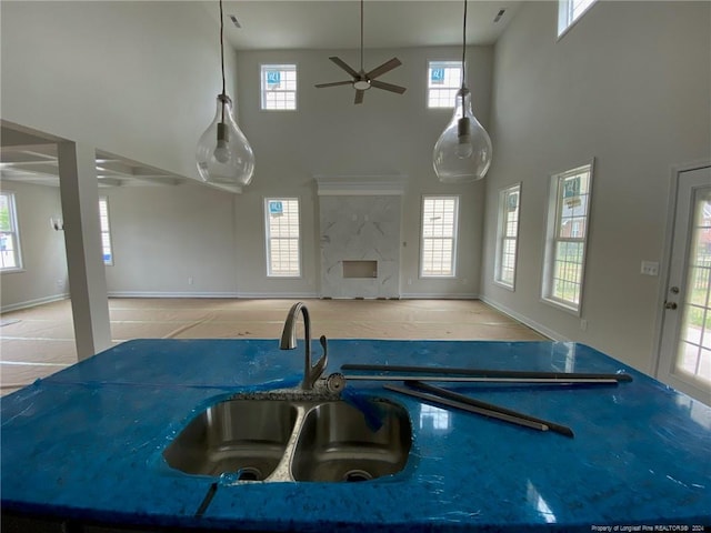 kitchen with a high ceiling, ceiling fan, a healthy amount of sunlight, and dark stone countertops